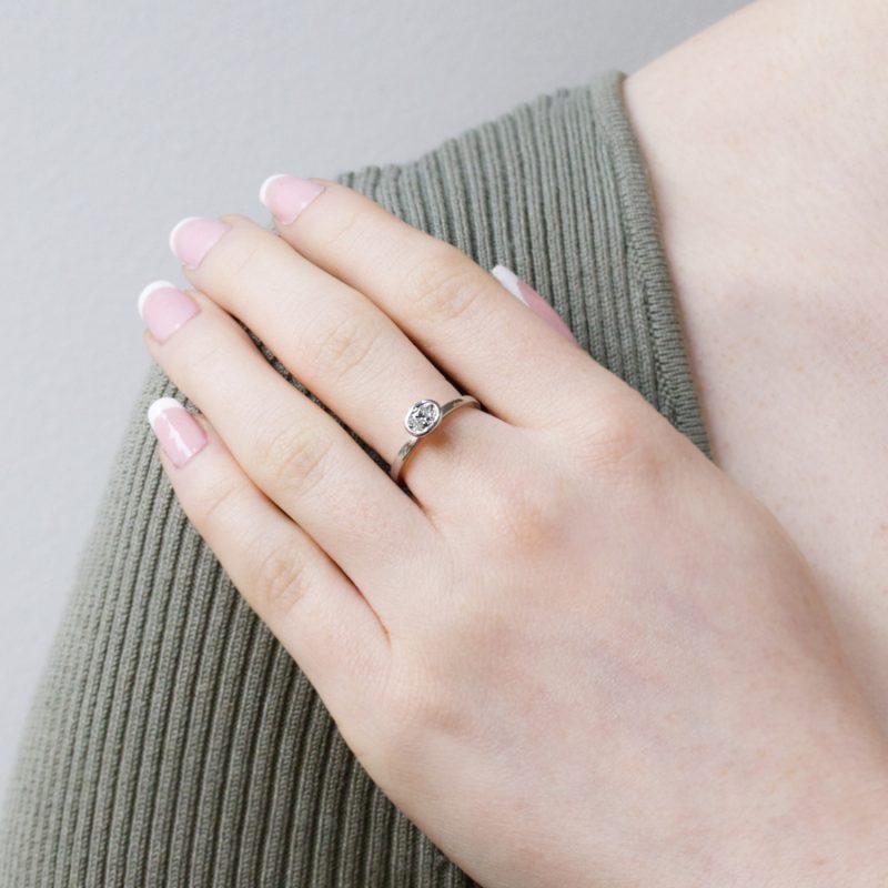 oval faceted diamond solitaire ring (0.4ct) in platinum, shown on model.