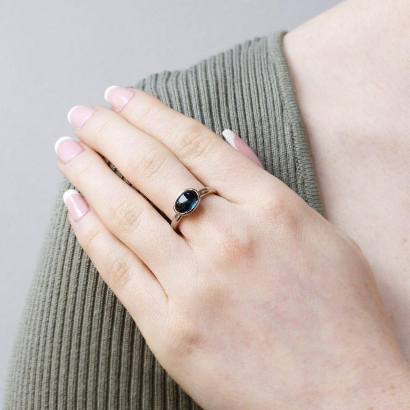 Oval cabochon blue tourmaline set in fairtrade 18ct white gold, shown on model.