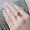 Claw-set cushion cut orange mandarin garnet ring in 18ct rose gold with a polished finish. Each claw is tipped with a bezel-set yellow diamond. Shown on model's hand.