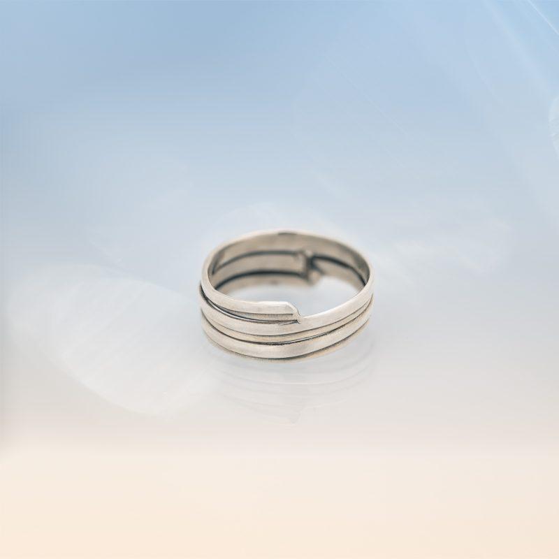 Modern silver wrap ring from the Force of Nature collection, featuring a layered band design, handcrafted in sterling silver and photographed on a soft gradient background.