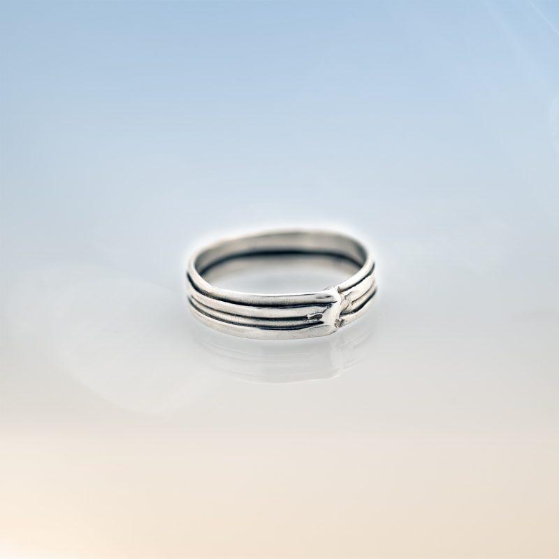 Modern silver wrap ring from the Force of Nature collection, featuring a layered band design, handcrafted in sterling silver and photographed on a soft gradient background.