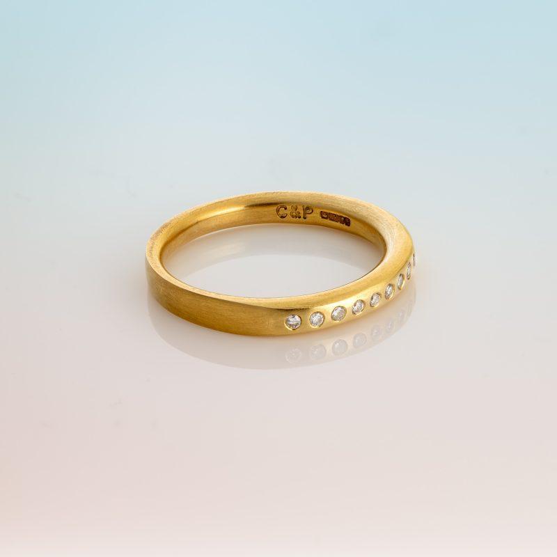 18ct yellow gold ring with eleven small round white diamonds set in a row.