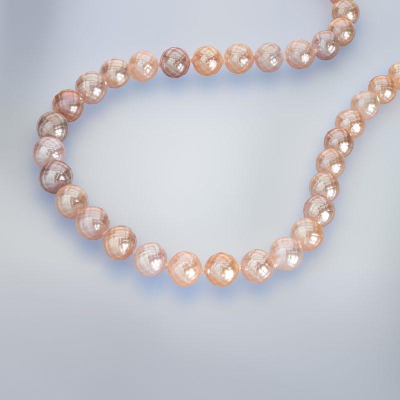 Faceted Pink Pearl Necklace laying down in a curved shape